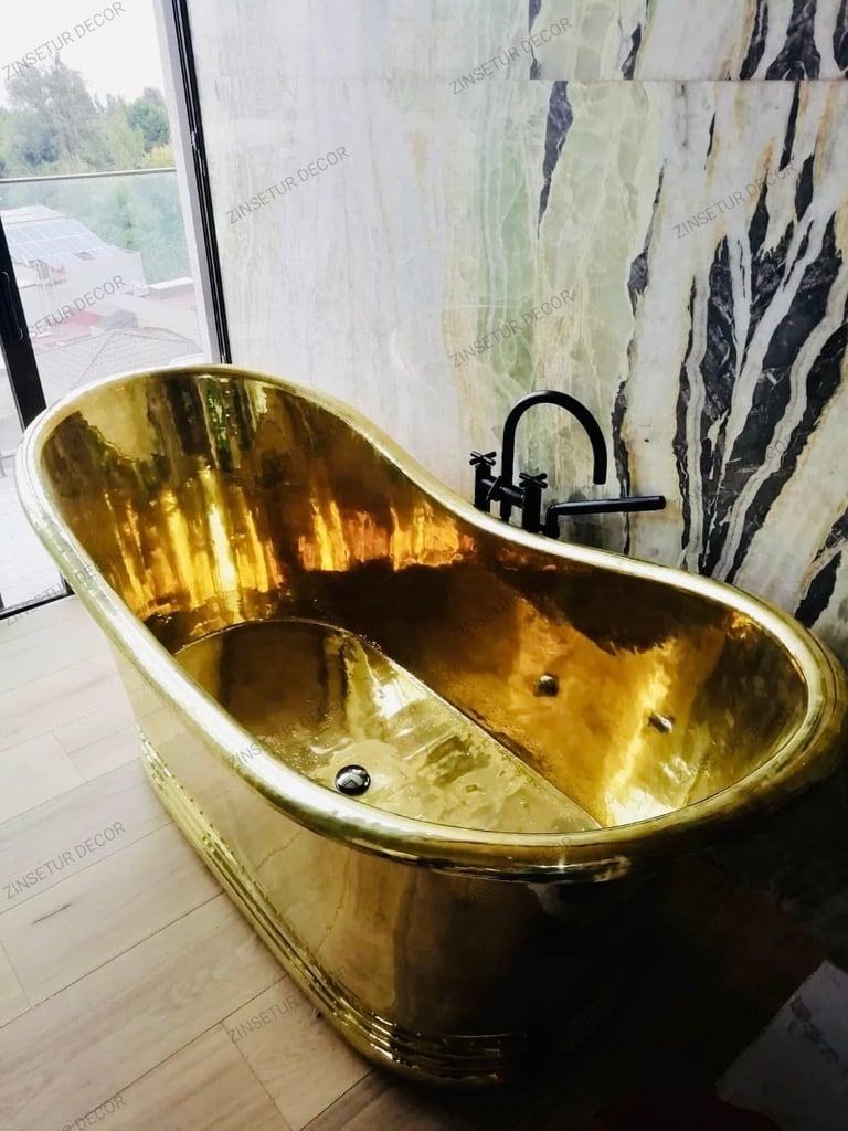 Gold-plated luxury bathtub in a modern bathroom with patterned wallpaper and window view