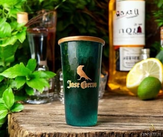 Jose Cuervo tequila branded green cup on wooden surface surrounded by limes, bottles, and green foliage
